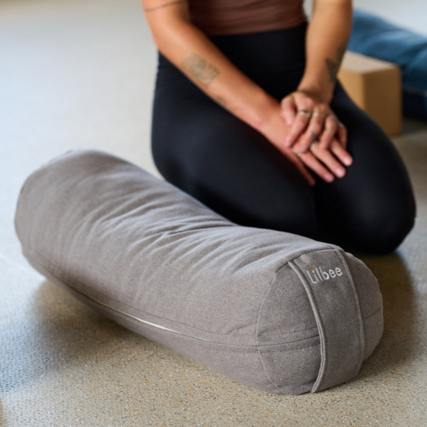 Close-up of a grey Lilbee round bolster on the studio floor. Soft yet supportive filling made from recycled fabric, ideal for yoga, stretching, and meditation. Handmade in Canada.