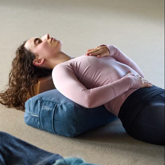 Man and woman relaxing in savasana with Lilbee rectangular bolsters under the knees and back. Eco-friendly yoga bolsters handmade in Canada with soft recycled-textile filling for restorative comfort.